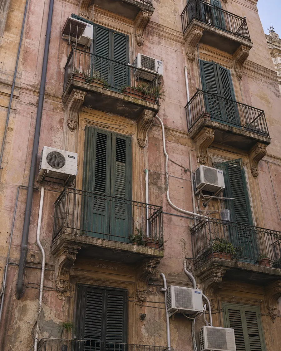 Facciata di un palazzo storico rovinata da tante unità esterne di climatizzatori e tubi